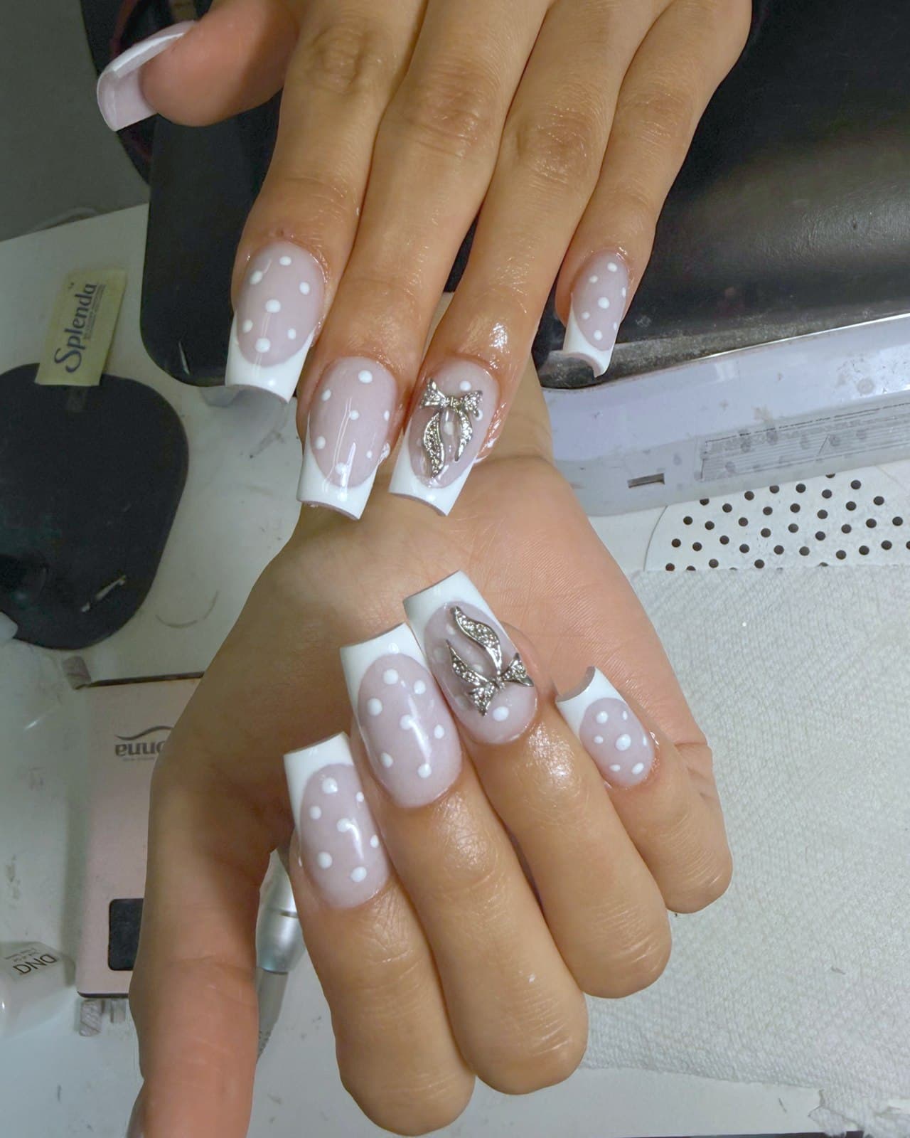 French blanche sur ongles carrés avec pois blancs et charm papillon argenté